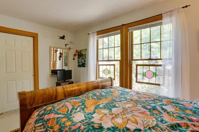 a bedroom with a bed with a colorful comforter and two windows at Less Than 1 Mi to Camelback Resort Home with Pool Table! in Tannersville