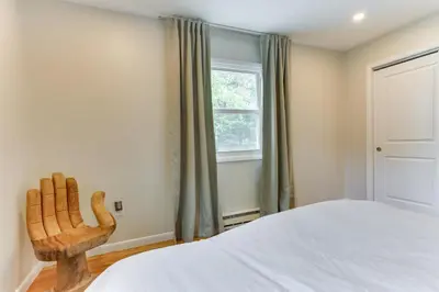 a bedroom with a bed and a wooden chair at Sauna, Fire Pit Spacious and Serene Poconos Getaway in Canadensis