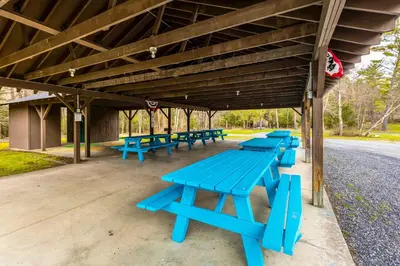 a group of blue picnic tables sitting under a pavilion at Sauna, Fire Pit Spacious and Serene Poconos Getaway in Canadensis