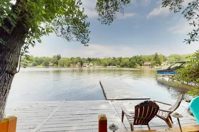 a dock with two chairs and a boat on a lake at Heaven on Lake Harmony in Lake Harmony