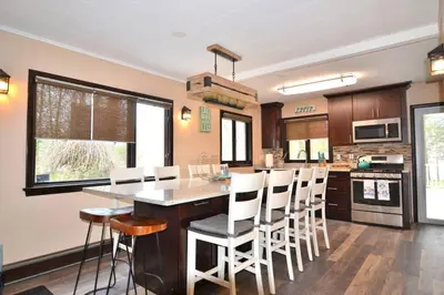 a kitchen with a large island with white chairs at 3 Acre Lake Paradise Swimming Pool & Jacuzzi HotTub! in Hopatcong