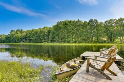a boat sitting on a dock next to chairs at Lakefront Catskills Container Home Private Lake in Swan Lake