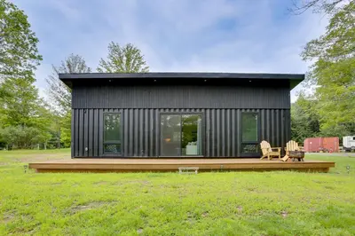 a small black house with a wooden deck at Lakefront Catskills Container Home Private Lake in Swan Lake