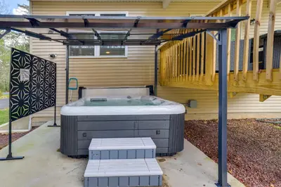 a hot tub sitting under a pergola on a patio at Hot Tub and Lake Access Spacious Tobyhanna Home in Tobyhanna
