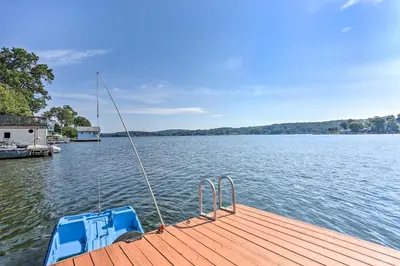 a boat tied to a dock on a lake at Spacious Lakefront House With a Private Dock in Hopatcong