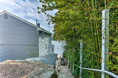 a house with a fence next to a building at Spacious Lakefront House With a Private Dock in Hopatcong