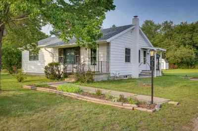 a white house with a garden in front of it at Quaint Horseheads Home about 9 Mi to Elmira College in Horseheads