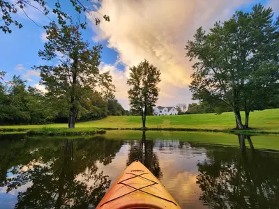 a kayak on a river with a house in the background at 13-Acre Private Estate, Private Lake, Private Golf Range, Private Forest & Hiking Trails in Ross Corner