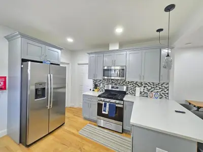 a kitchen with stainless steel appliances and white cabinets at Large Group Home NJ Close To NYC Train in Boonton