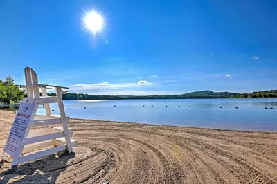 a lifeguard chair sitting on a beach next to a lake at Walk to Beaches Tree-Lined Pocono Lake Retreat! in Pocono Lake