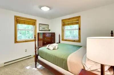 a bedroom with a bed and two windows at Walk to Beaches Tree-Lined Pocono Lake Retreat! in Pocono Lake