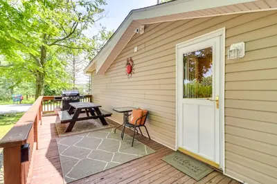 a wooden deck with a white door and a picnic table at Walk to Beaches Tree-Lined Pocono Lake Retreat! in Pocono Lake