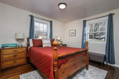 a bedroom with a bed and a dresser and two windows at The Craftsman's Homestay in Gordonville