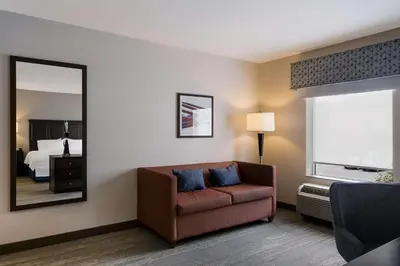 a living room with a couch and a mirror at Hampton Inn & Suites Wilmington Christiana in Newark
