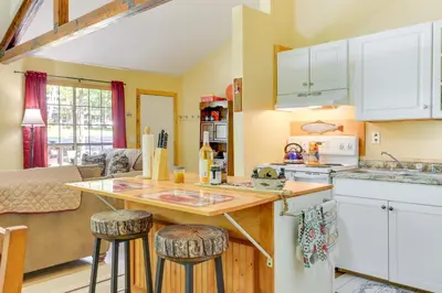 a kitchen with white cabinets and a counter with stools at Pools and Ski Access Lackawaxen Cottage with Deck! in Lackawaxen