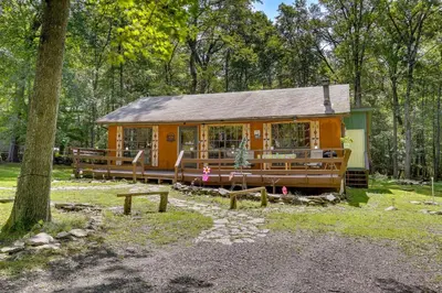 a small cabin in the middle of a forest at Pools and Ski Access Lackawaxen Cottage with Deck! in Lackawaxen