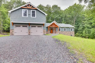 a house with two garage doors on a gravel driveway at Cresco Countryside Oasis Surrounded by Nature! in Cresco