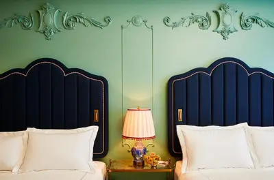 a bedroom with two beds and a table with a lamp at The Fifth Avenue Hotel in New York