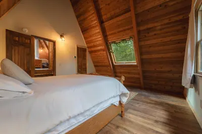 a bedroom with a white bed in a log cabin at Enchanting River- Water Front A-Frame Cabin in Yulan