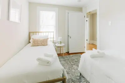 two beds in a bedroom with white walls at Quaint Boho Home in Lancaster City in Lancaster