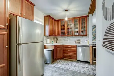 a kitchen with wooden cabinets and a stainless steel refrigerator at Cozy Dark & Moody Home New Reno 10 mins to Lanc in Mountville