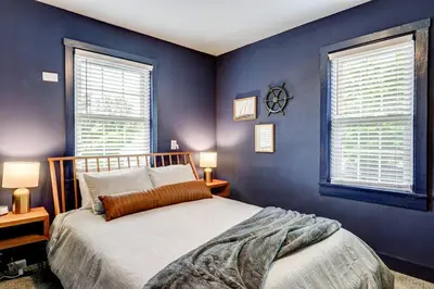 a blue bedroom with a bed and two windows at Cozy Dark & Moody Home New Reno 10 mins to Lanc in Mountville