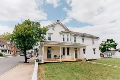 a white house with a porch on a street at Newly Renovated Vintage Inspired Large 4 BR Home in Mount Joy
