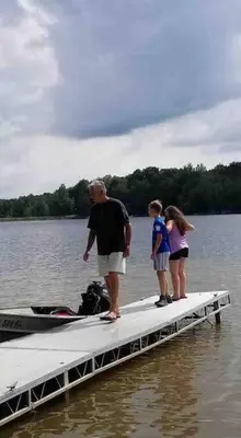 a man and two children standing on a dock in the water at Tranquil Getaway in the Pocono Mountains in Thornhurst