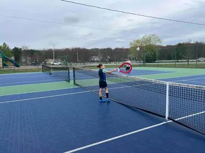 a young boy hitting a tennis ball with a racket at Tranquil Getaway in the Pocono Mountains in Thornhurst