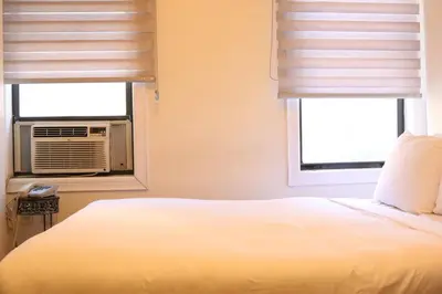 a bedroom with a white bed and two windows at Midtown West Hotel in New York