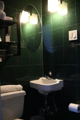 a green tiled bathroom with a sink and a mirror at Midtown West Hotel in New York