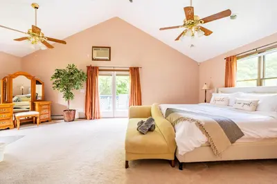 a bedroom with a large bed and a chair at Bethel Woods Retreat - wPool, Hot Tub & Arcade! in Mongaup Valley