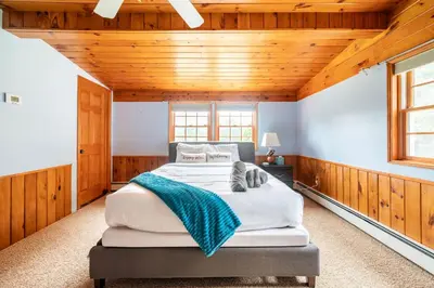 a bedroom with a large bed in a room with wooden walls at Bethel Woods Retreat - wPool, Hot Tub & Arcade! in Mongaup Valley