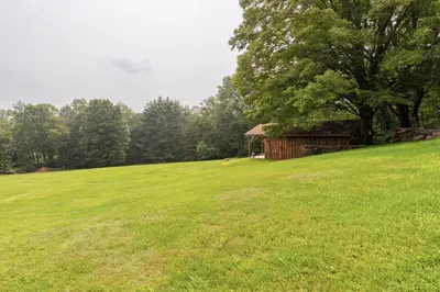 a grassy field with a cabin in the background at Bethel Woods Retreat - wPool, Hot Tub & Arcade! in Mongaup Valley