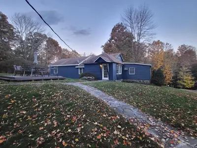 a blue house with a patio in the yard at Bethel Woods Retreat - wPool, Hot Tub & Arcade! in Mongaup Valley