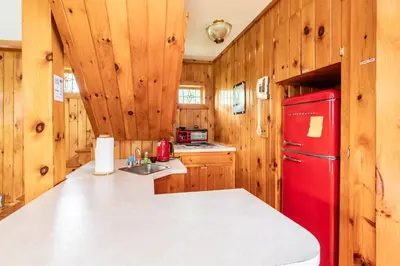 a kitchen with a red refrigerator and wooden walls at Bethel Woods Retreat - wPool, Hot Tub & Arcade! in Mongaup Valley