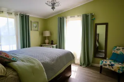 a bedroom with green walls and a bed and a mirror at Farm Country House with Pool and Huge Property in Blakeslee