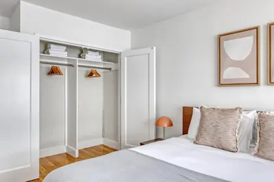 a white bedroom with a bed and a mirror at Midtown E 1BR w Gym Doorman nr the 6 NYC-4 in New York