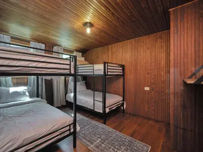 a bunk room with two bunk beds and a chair at Luxuriously Restored Farm Cabin in Mountainhome