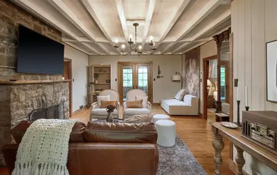 a living room with a couch and a stone fireplace at Luxuriously Restored Farm Cabin in Mountainhome