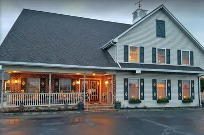 a white house with a porch with orange doors at Country Living Inn in Lancaster