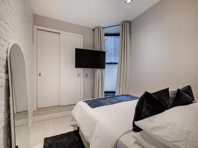 a bedroom with a bed and a tv on the wall at Cozy & Convenient Midtown Condo-Hotel! in New York