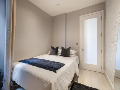 a white bedroom with a bed with black pillows at Cozy & Convenient Midtown Condo-Hotel! in New York