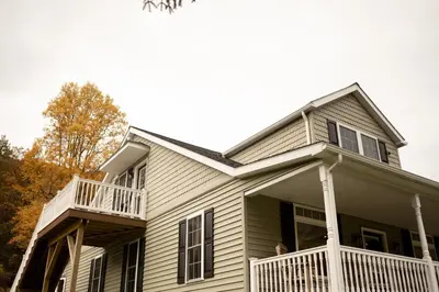 a family sitting on the porch of a house at Historic Sears River Home (Main Level) on 10 Acres in Tamaqua