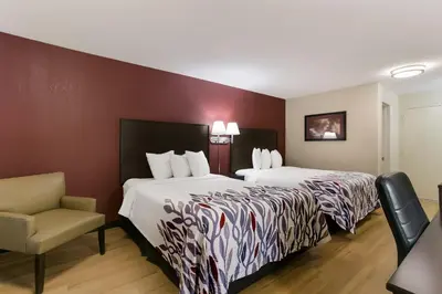 a hotel room with two beds and a chair at Red Roof Inn Hershey in Hershey