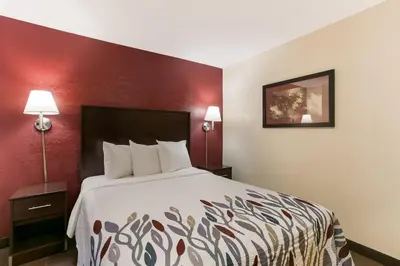 a hotel room with a bed and a red wall at Red Roof Inn Hershey in Hershey
