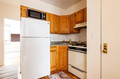 a kitchen with wooden cabinets and a white refrigerator at ✪ Large 2 Bedrooms ✪ Queen Beds ✪ Work Stations in New York
