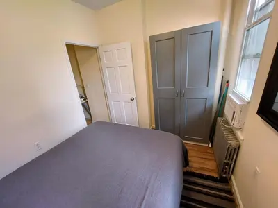 a bedroom with a bed and a door and a window at Comfortable Apartment with Workstation in New York