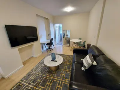 a living room with a black leather couch and a tv at Comfortable Apartment with Workstation in New York