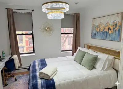 a bedroom with a white bed and a chandelier at Comfortable 2BR & 2 Bath Apt in Downtown NYC in New York